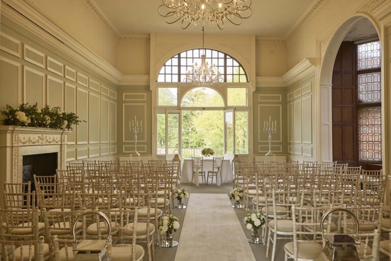 The panelled Winchester Suite set with chairs for a ceremony, facing a fanlight window and doors onto a balcony over the gardens, Farnham Castle