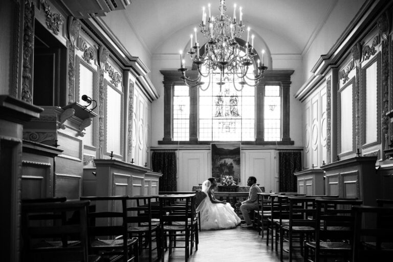 The 17th-century Bishop's Chapel, with carved wooden panelling, a chandelier and the altar window, in black and white, Farnham Castle