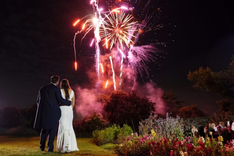 A couple watching a firework display over the gardens at night, Farnham Castle