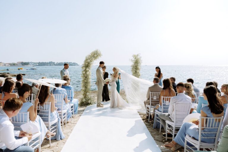 Guests seated either side of a white aisle for a ceremony on the Istrian coast, Flammeum