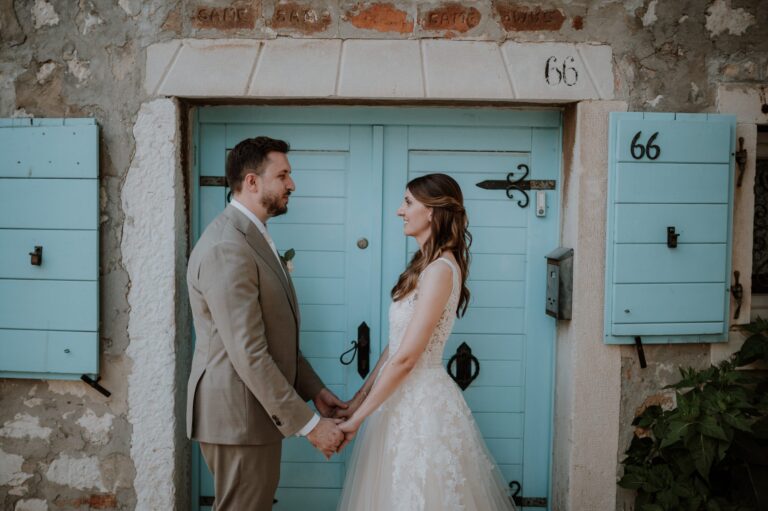 A couple holding hands before a pale blue door in an Istrian stone village, Flammeum