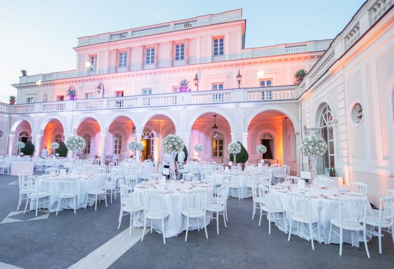 Villa Miani illuminated at dusk, tables set beneath tall white pedestal arrangements, Flavia Bruni