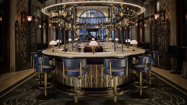 Round bar of MÚZSA with blue chairs and an overhead glass rack, Four Seasons Hotel Gresham Palace