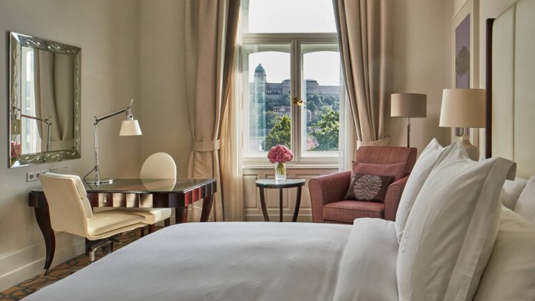 Guest room with large bed, desk and view through a tall window, Four Seasons Hotel Gresham Palace