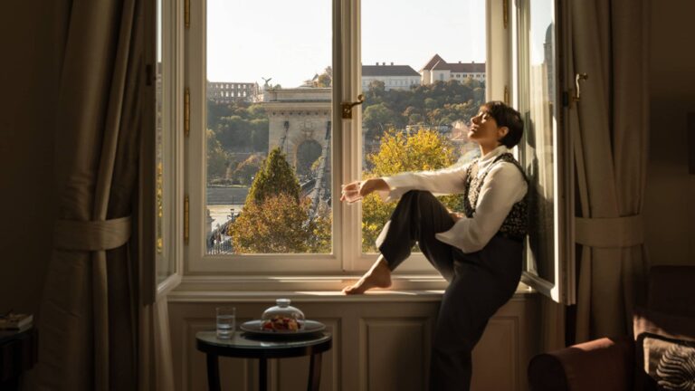 Guest at a window with a view towards Buda Castle, Four Seasons Hotel Gresham Palace