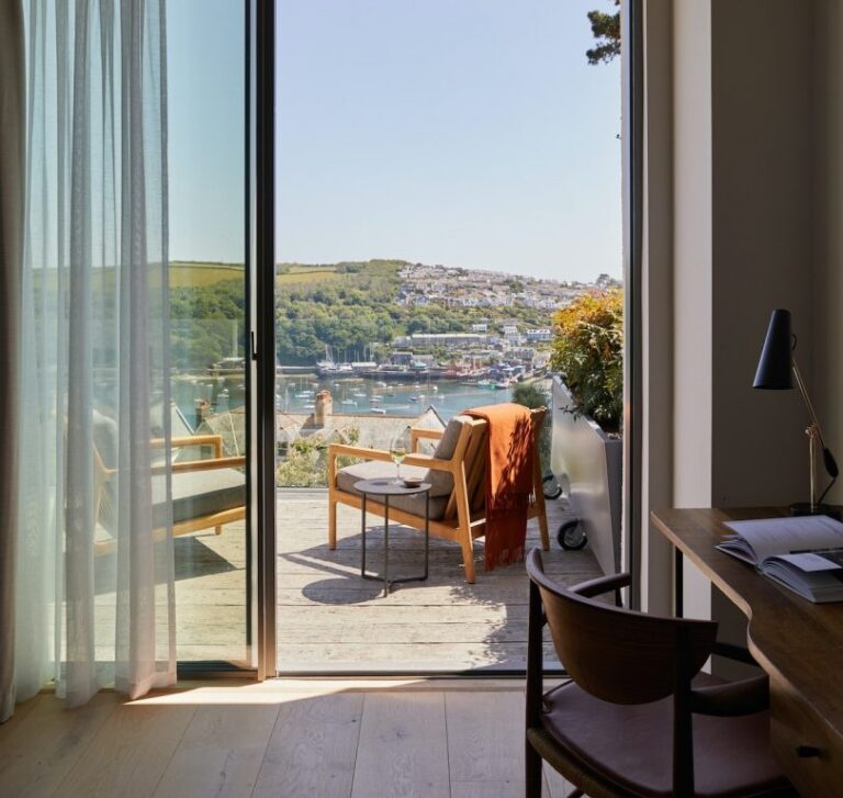 A guest suite with a balcony and open doors framing a view over the Fowey estuary, Fowey Hall