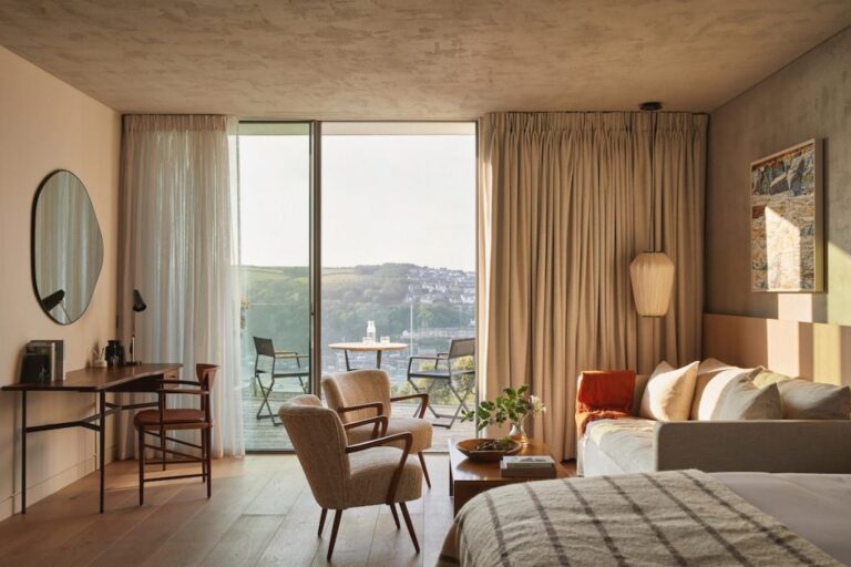 A bedroom with mid-century chairs framing a view over the estuary, Fowey Hall