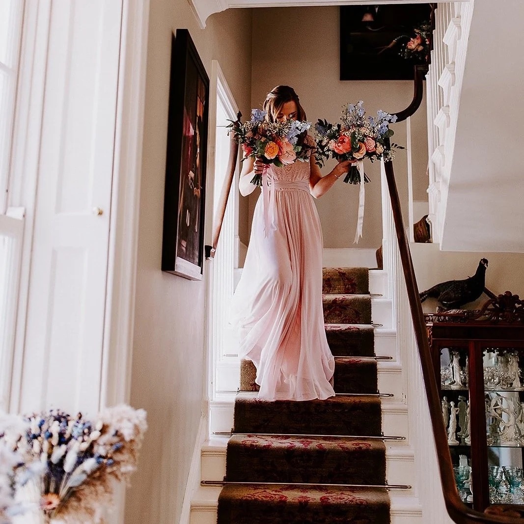 Carrying matching bouquets down a country house staircase, Foxgloves and Roses