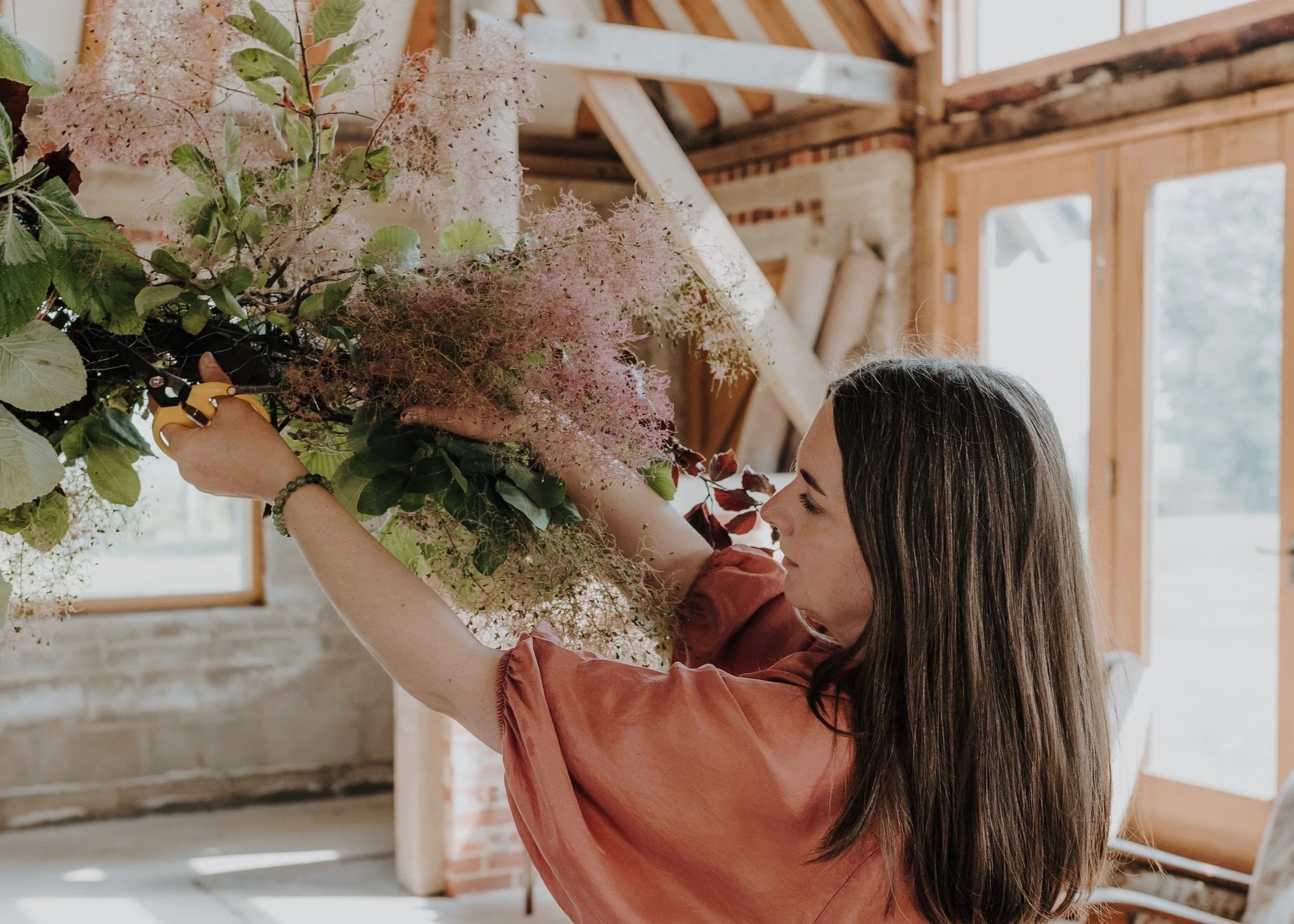 Nicola building a smoke bush and rose installation, in the studio barn, Foxgloves and Roses