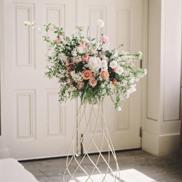 A pedestal installation of peach rose and white cow parsley, Foxgloves and Roses