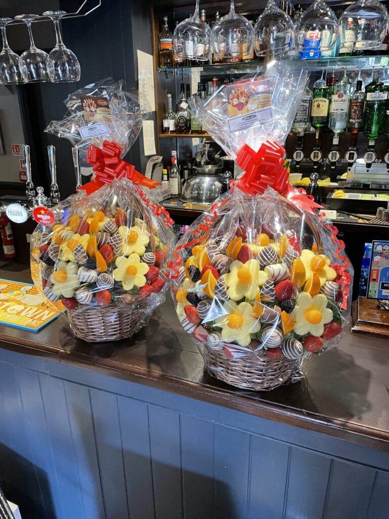 Two cellophane wrapped edible arrangements ready for delivery, Fruity Gift