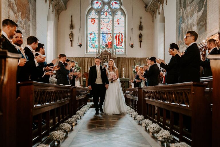 A wedding party leaving Bishop Tait's Chapel after their service, beneath its painted walls and stained glass, Fulham Palace