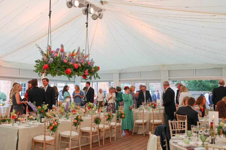 Tables set in the Chaplain's Marquee, the canopy pale above pressed linen and glassware, Fulham Palace
