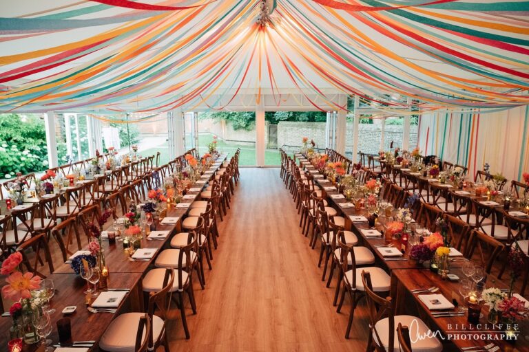 Long banqueting tables in the Chaplain's Marquee beneath a draped ceiling, dressed for a celebration, Fulham Palace