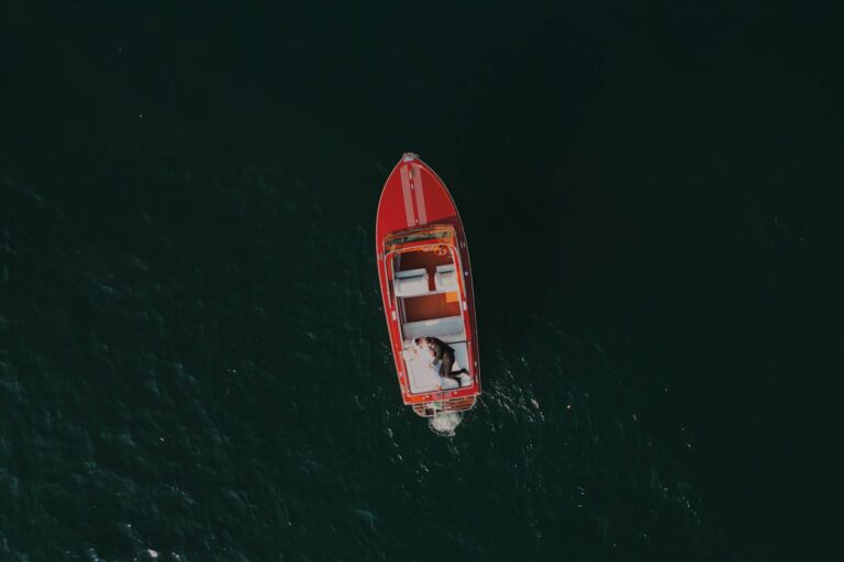 Overhead drone shot of a couple in a red wooden boat on Lake Como, from Bobbi and George's elopement, Gaetano Di Giacomo Media Production