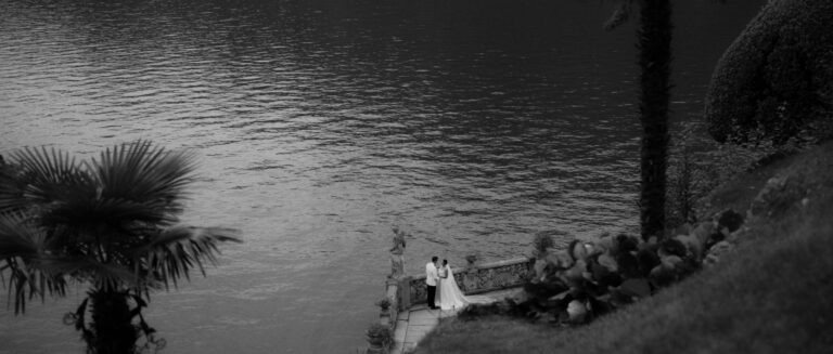 A couple at the water's edge below Villa del Balbianello, Lake Como, in black and white, Gaetano Di Giacomo Media Production