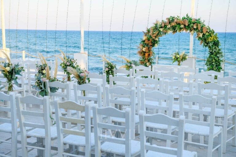 Rows of white chairs facing a floral arch and the sea for the ceremony, Galu Seaside