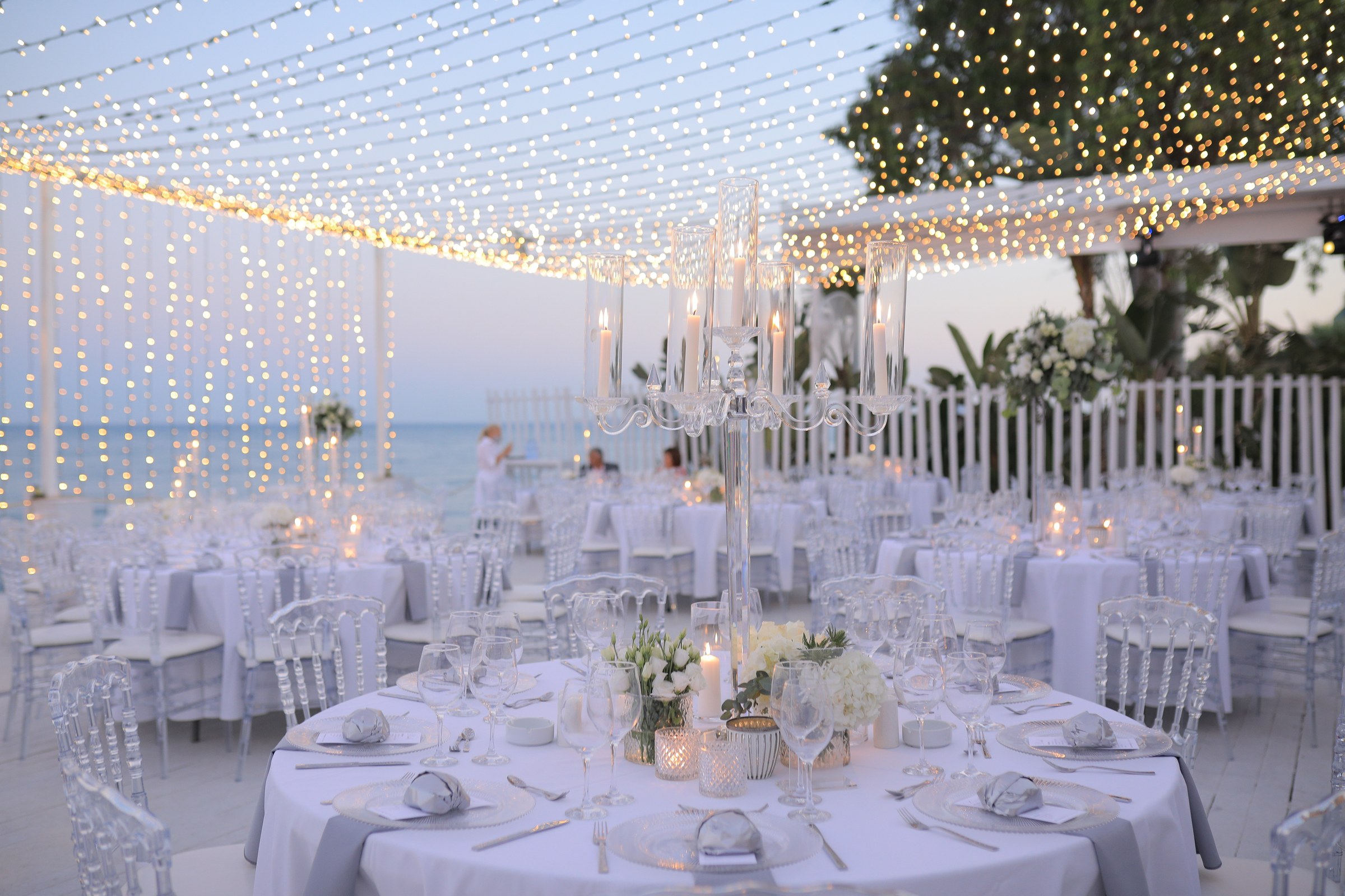 Tables dressed in white beneath the canopy of lights on the seafront deck, Galu Seaside