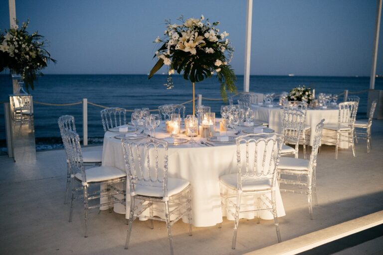 A single table on the deck at dusk, with a tall floral centrepiece, Galu Seaside