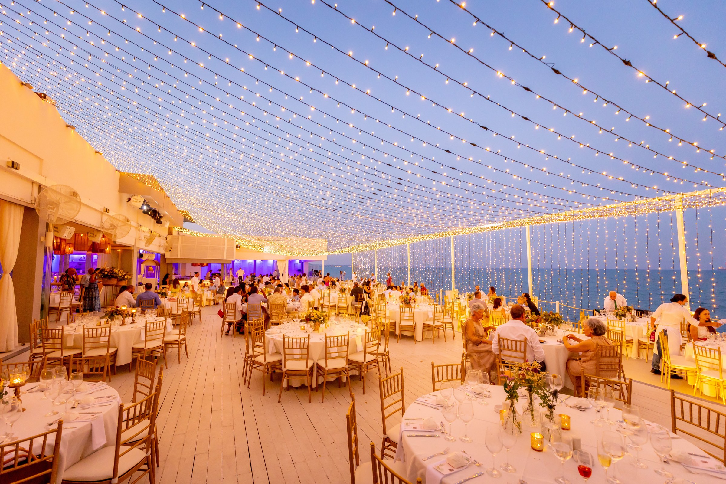 Wedding reception on the deck lit by fairy lights at dusk, Galu Seaside