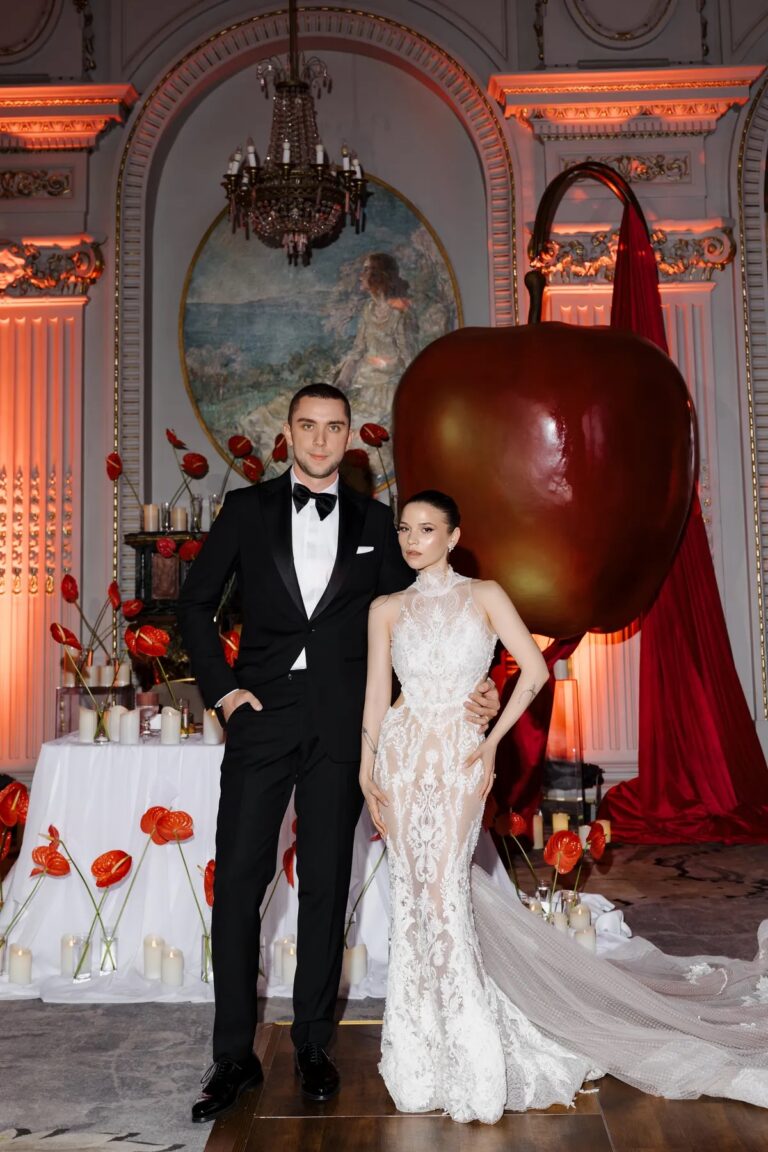Couple at a red and ivory styled dessert table with an oversized apple, Geta Ungurean Agency