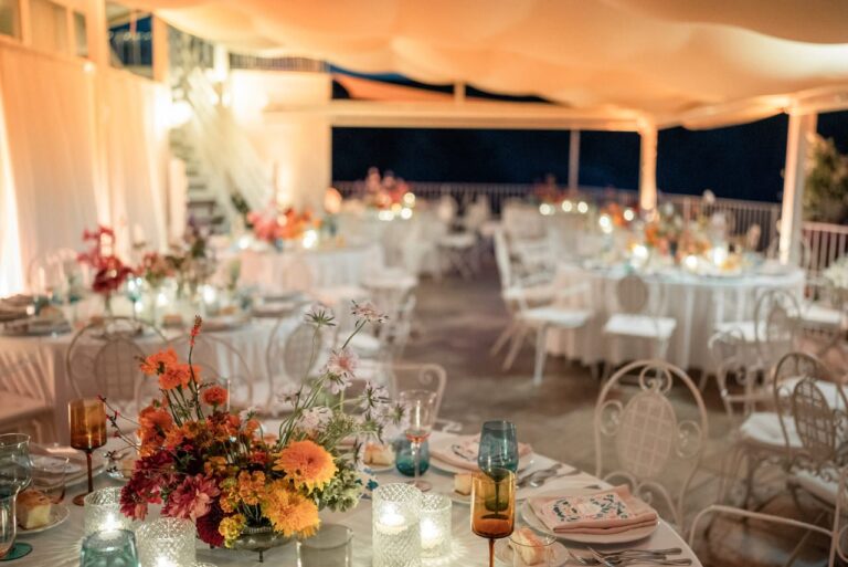 Candlelit dinner tables with orange and red flowers on a covered terrace on Ponza, Giandomenico Cosentino Photography