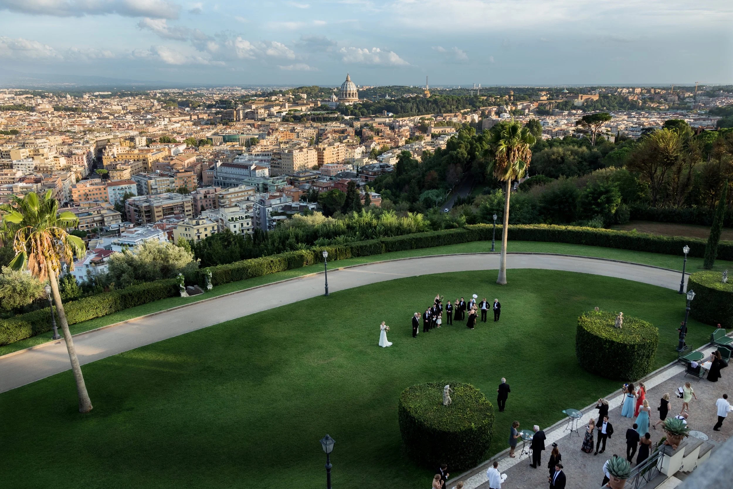An outdoor ceremony on the lawn at Villa Miani, Rome, seen from above with the city beyond, Giuliano Bausano