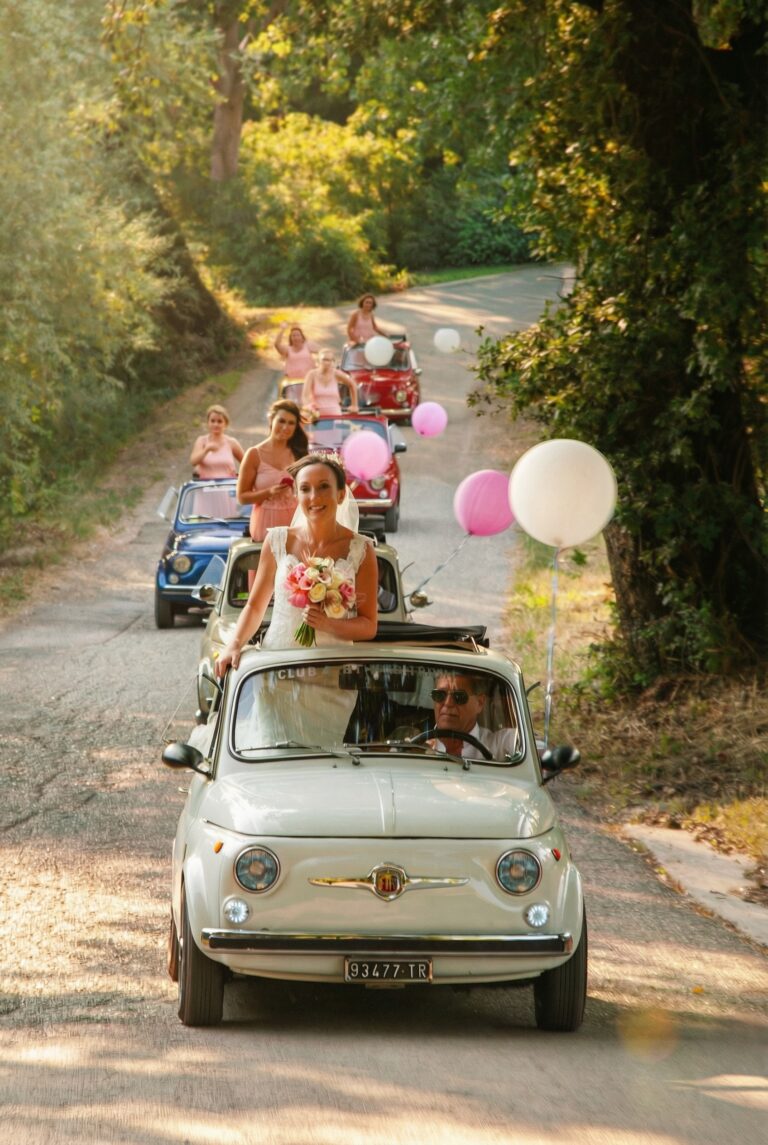 A convoy of vintage Fiat 500s with balloons on a country road, Giuliano Bausano