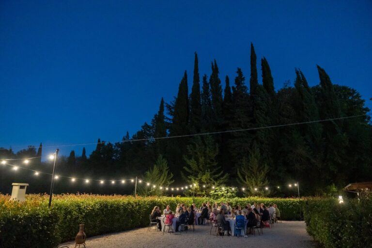 Dinner outdoors under string lights at dusk, Fattoria del Colle, Giuliano Bausano
