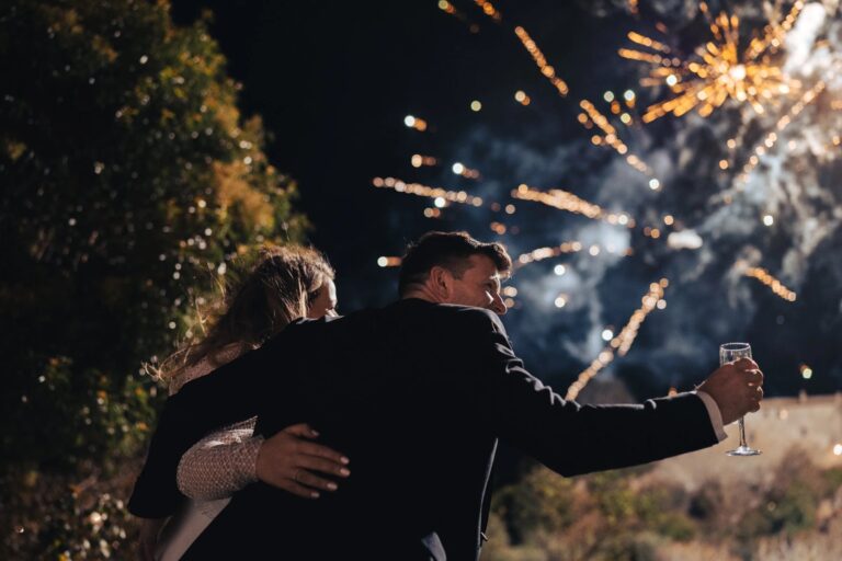 A couple embracing as fireworks go off above them at Borgo di Tragliata, Giuliano Bausano