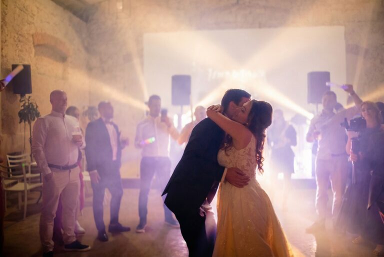 The couple kissing on a lit dance floor surrounded by guests, Laura and Bob's wedding, Giuliano Bausano