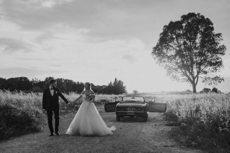 The couple walking from a vintage car past a lone tree, in black and white, Salento, Giuseppe Suma Weddings