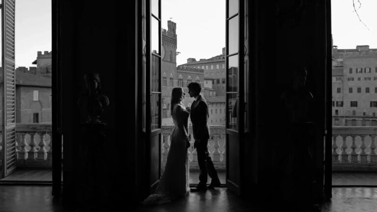 The couple silhouetted on a balcony above the rooftops of Siena, Giuseppe Suma Weddings