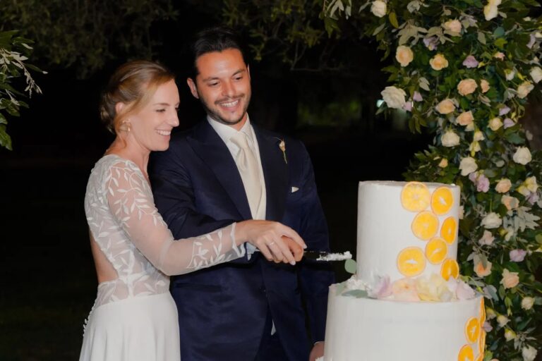 Cutting a lemon-decorated cake at night beside a flower arch, Puglia, Giuseppe Suma Weddings