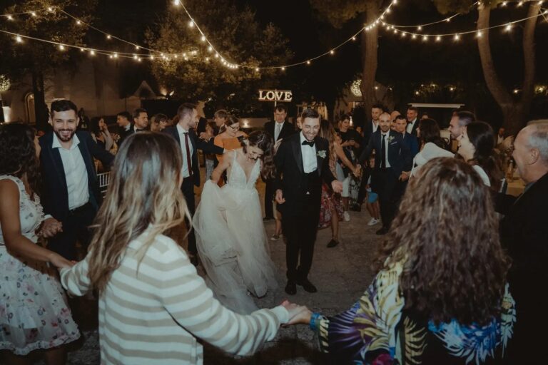 Guests dance around the couple under festoon lights, Valle d'Itria, Puglia, Giuseppe Suma Weddings