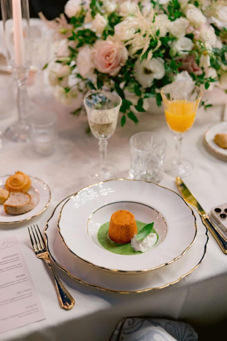 A place setting in Tuscany with gold-rimmed china and gold cutlery, crystal glasses and a centrepiece of white and blush roses, Glam Events in Tuscany