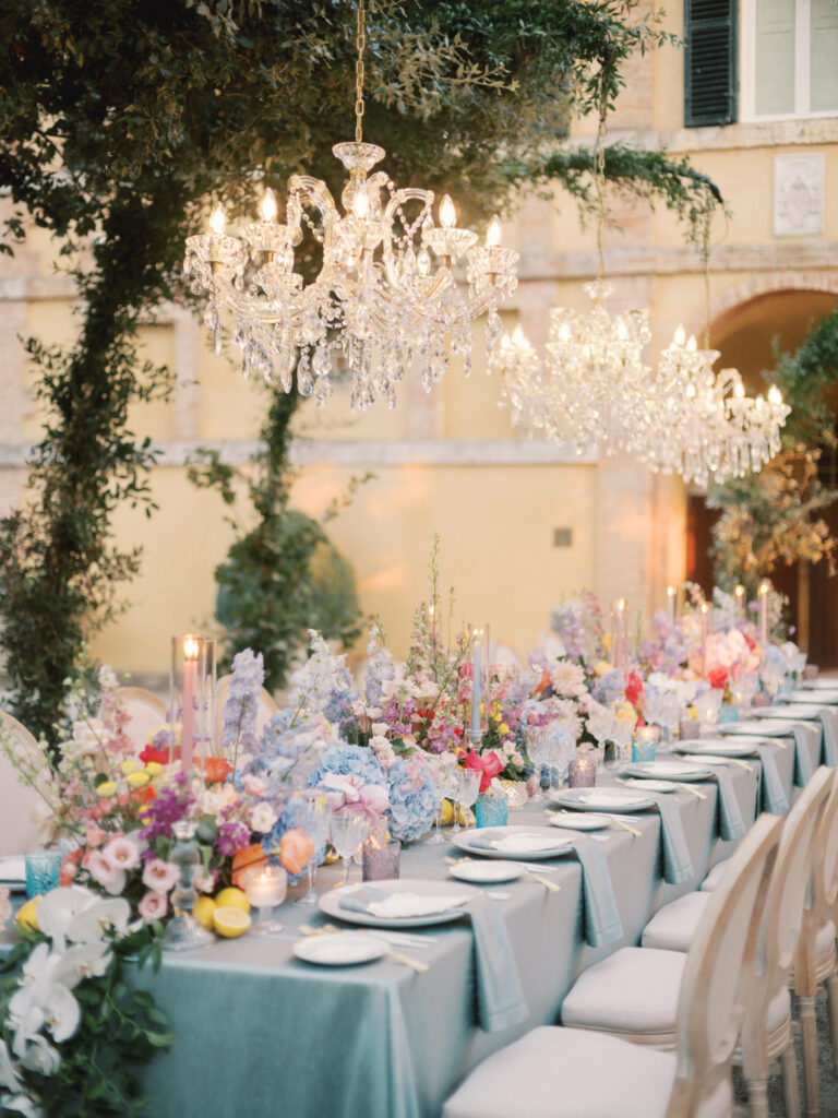 Siyu and Teng's dinner at La Foce, Tuscany: a chandelier hung from the trees above a table of wild flowers and lemons, the villa facade behind, Glam Events in Tuscany