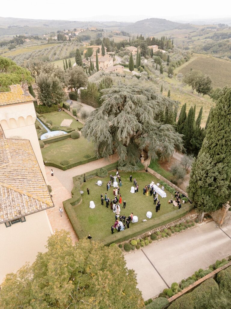 From above: drinks on a villa lawn under a cedar, the Tuscan hills and vineyards running away behind, Glam Events in Tuscany