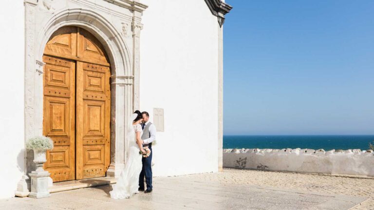 Couple outside a whitewashed chapel with a carved timber door, Algarve, Glamour Algarve Weddings