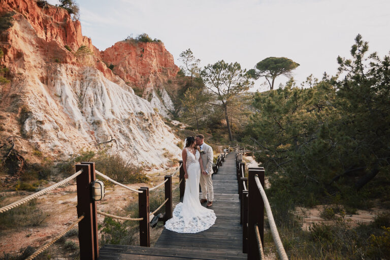 Bride on a wooden boardwalk beneath red Algarve cliffs, Go2Wonderland