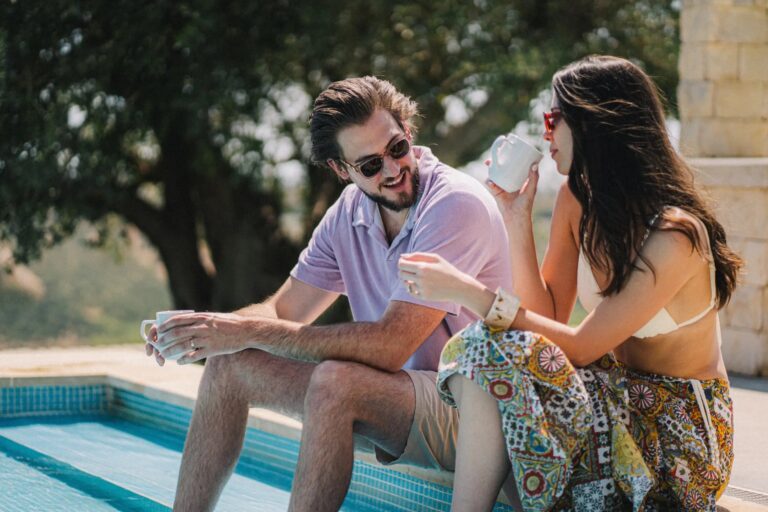 A couple sharing coffee beside a villa pool during their elopement in Sicily, Gordon Wedding Films