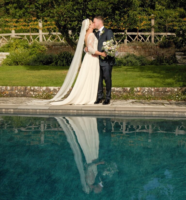 The couple kissing beside a garden swimming pool, reflected in the water, Gorgeous Films