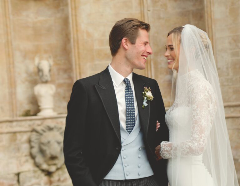 Bride and groom in a stone courtyard, the groom in morning dress, Gorgeous Films