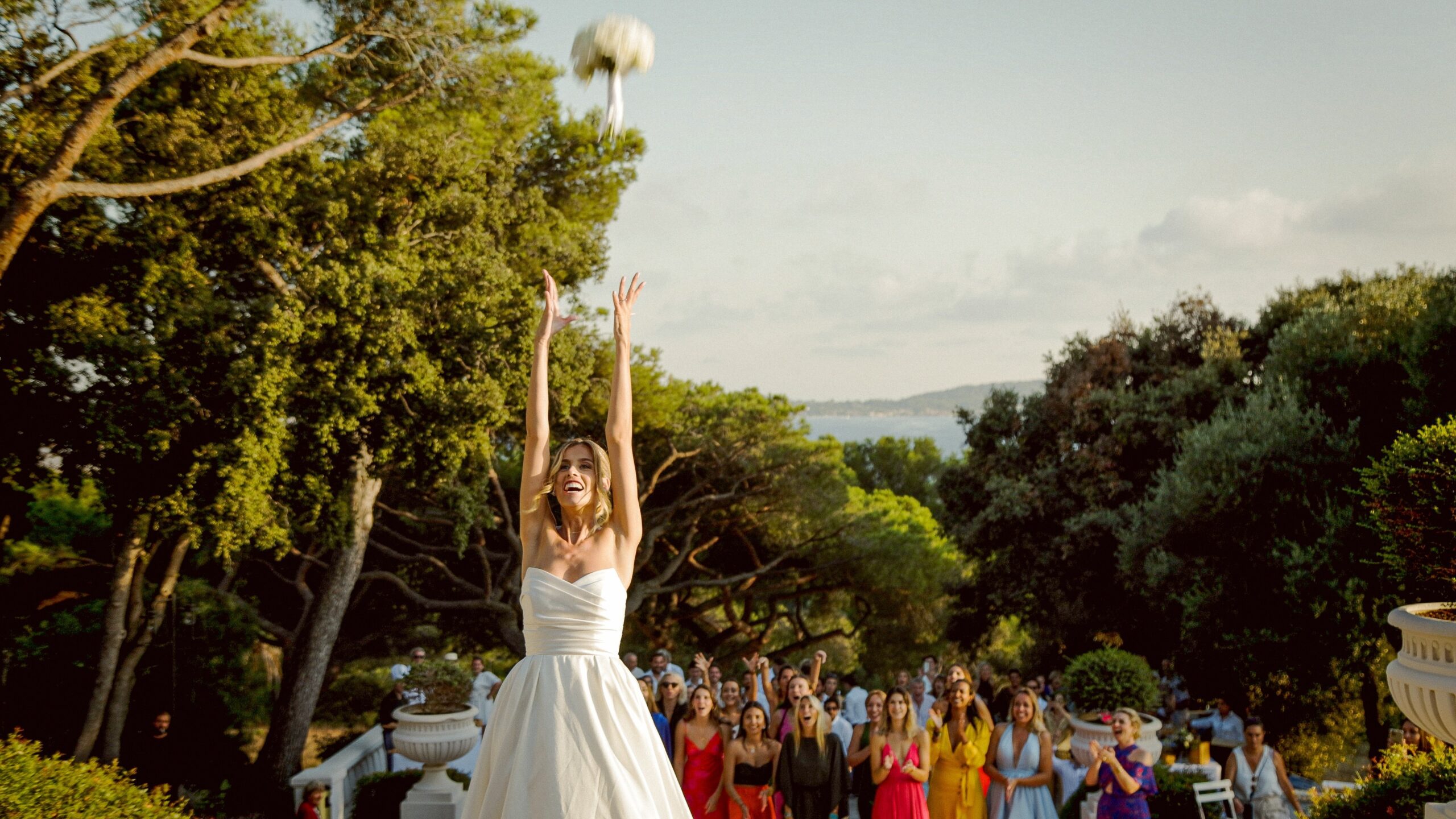 The bride throws her bouquet on a pine-shaded terrace above the sea, from Margaux and Arthur's wedding in Provence, Gorgeous Films