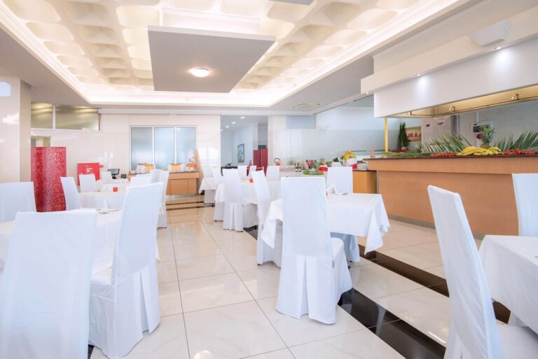 A restaurant interior with white chairs, Grand Blue Kos Hotel