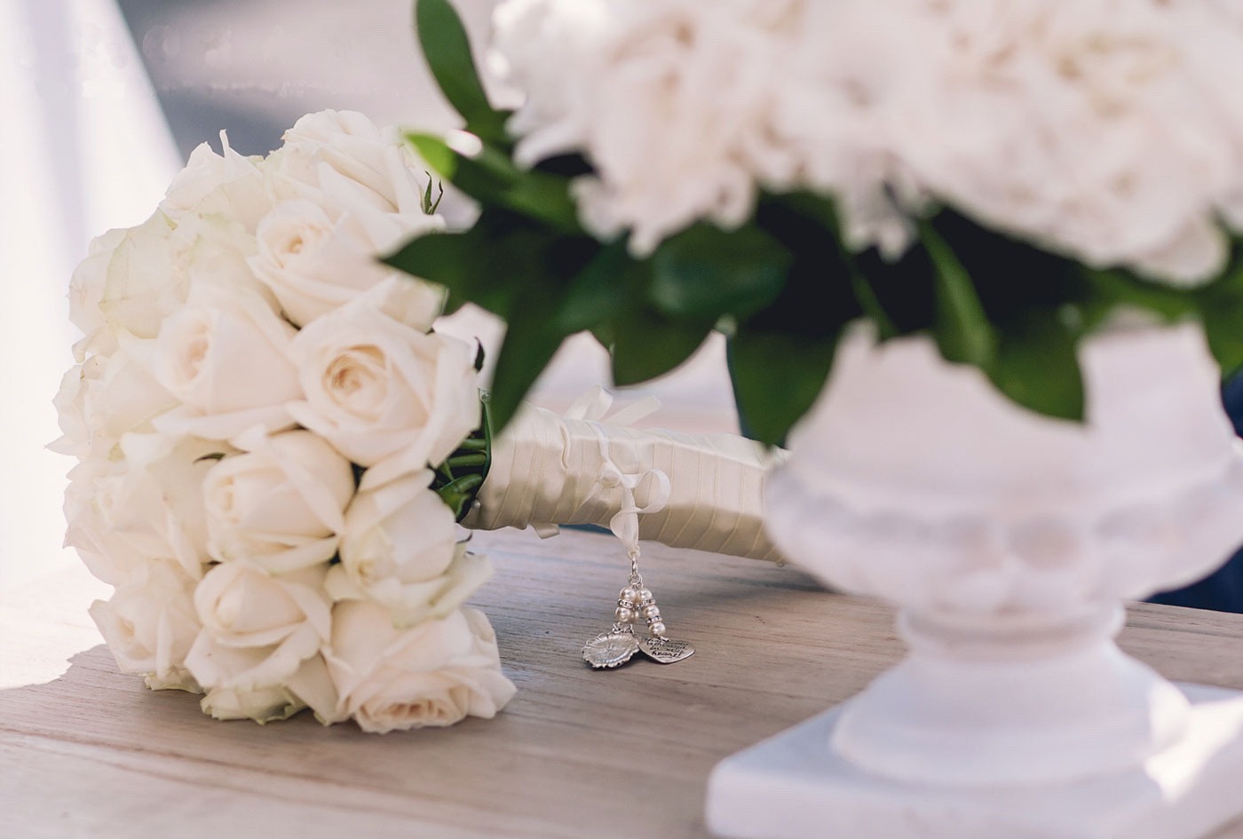Bouquet of white roses with a charm on a wooden table, Greek Dream Planners