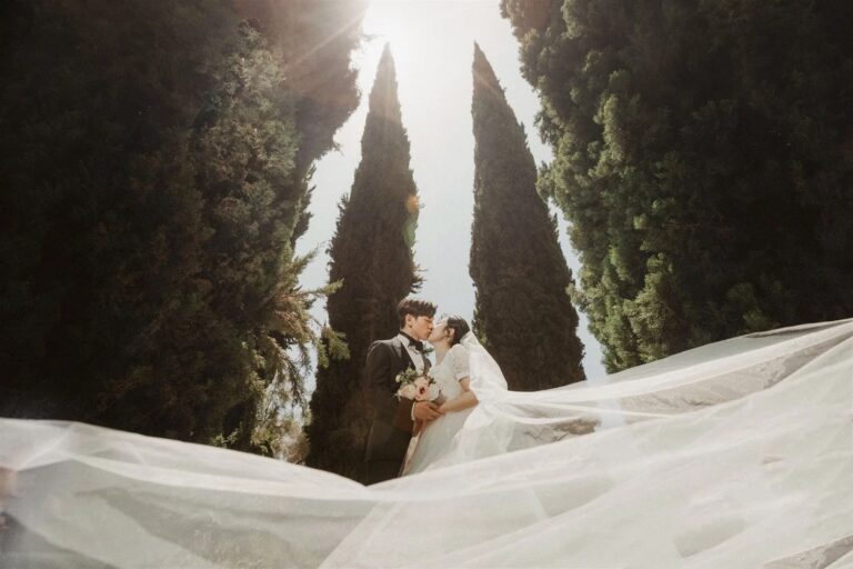 A couple kiss beneath a veil in the cypress allee, courtesy of Lulan Studio, Greystone Mansion
