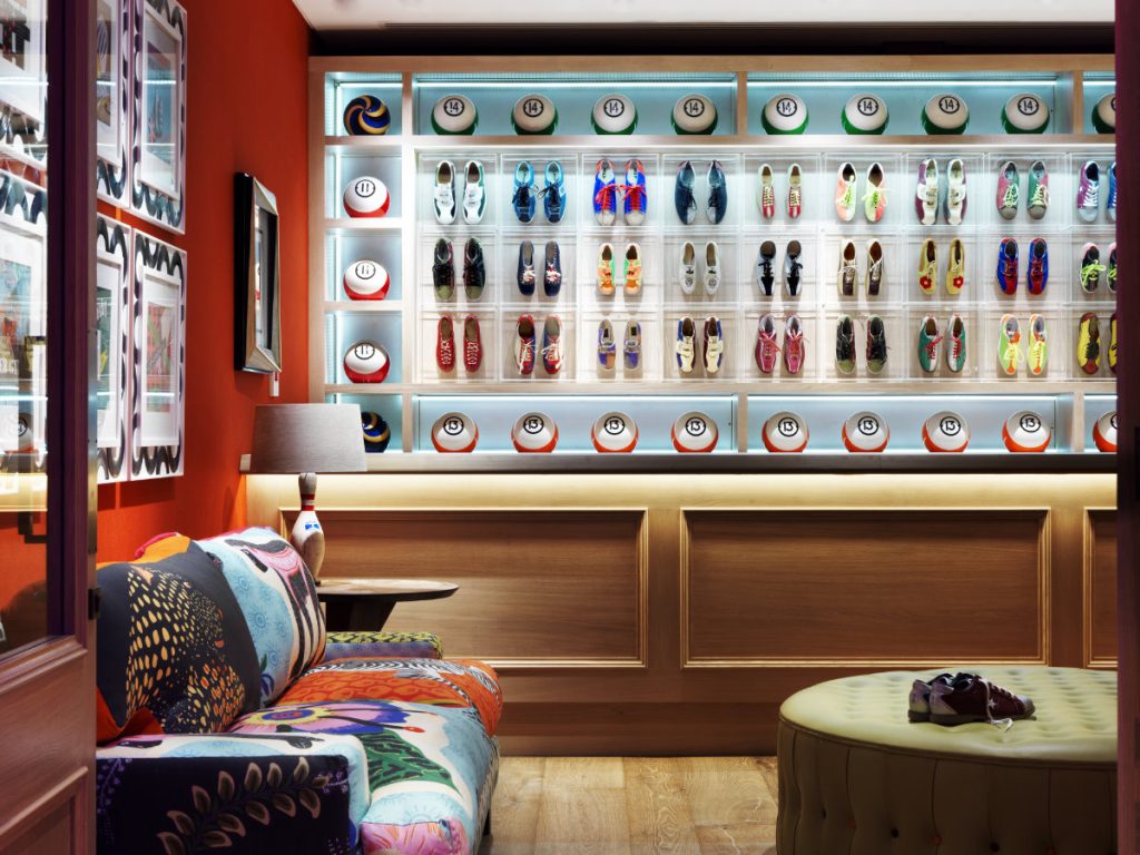 A lounge with a wall of bowling shoes and a patterned sofa