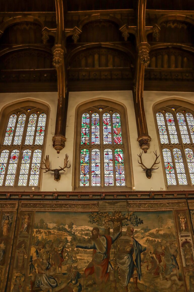 Tudor tapestries and mounted antlers beneath the Great Hall's stained-glass windows, Hampton Court Palace