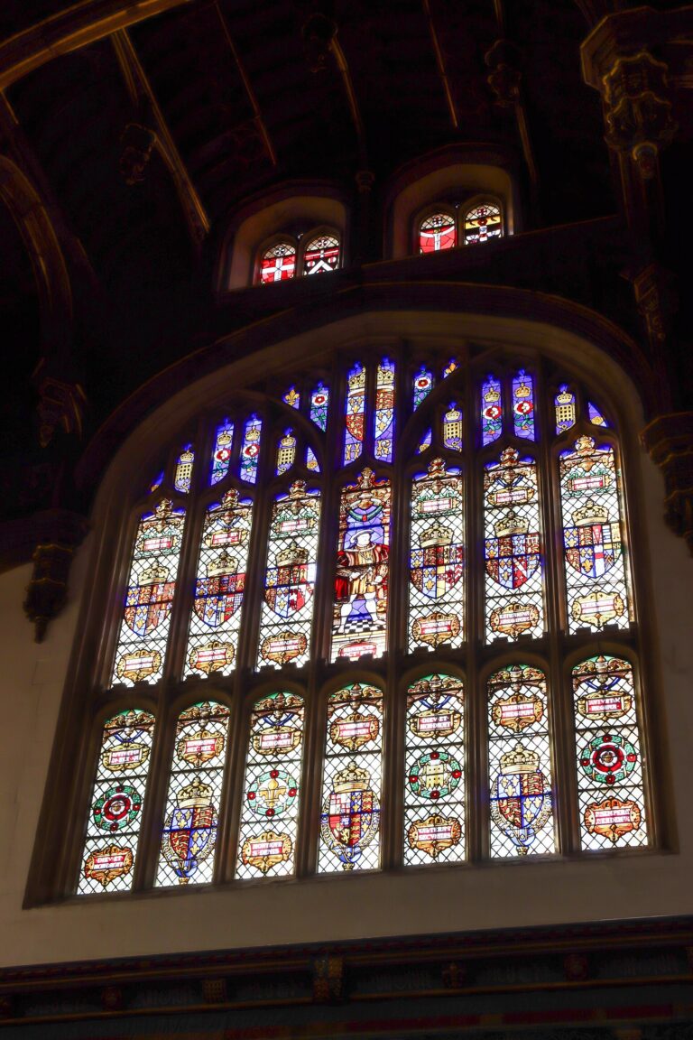 The Great Hall's soaring stained-glass window, heraldic glass set in dark timber, Hampton Court Palace